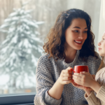 Mother and daughter drinking hot chocolate near a snowy window - AFUE 80% vs AFUE 90% Furnaces: What's the Difference?