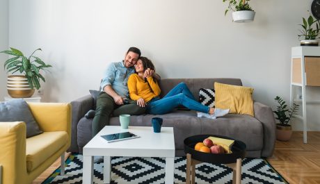 Embraced couple relaxing together on their sofa at living room in home. Happy couple having romantic moment