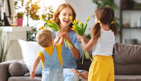 Happy mother's day! Children congratulates moms and gives her a gift and flowers